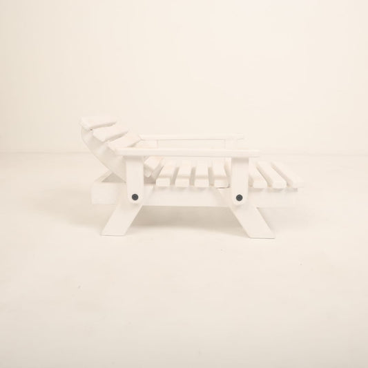 A mini wooden beach bench surrounded by sand and seashells, styled as a coastal-themed baby photoshoot prop for creating a beach-inspired setting.