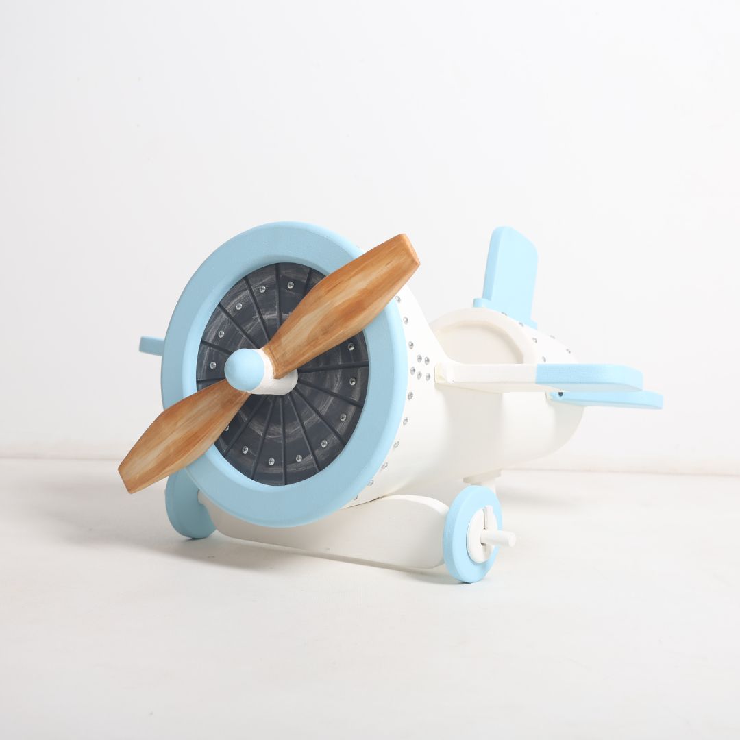 A wooden aeroplane baby photoshoot prop with smooth edges, painted in soft pastel colors, designed to hold a newborn comfortably. The prop features a vintage airplane design with mini wings and a tail, perfect for creating whimsical, aviation-themed baby portraits.