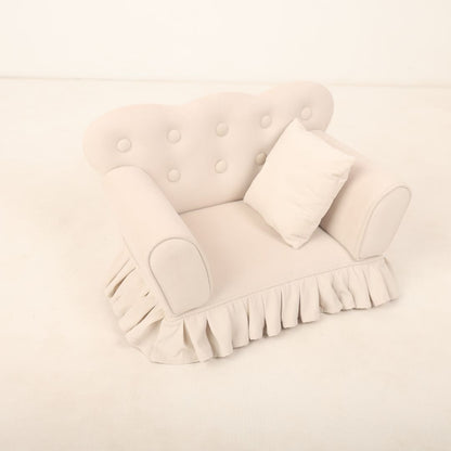  A small, cozy sofa prop designed for baby photoshoots, featuring soft cushions and neutral tones. The sofa is perfectly sized for newborns or infants or toddlers, creating a charming setting ideal for capturing adorable photos