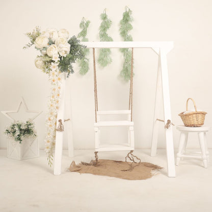 Wooden swing baby prop with soft cushions and decorative ropes, designed for newborn and toddler photoshoots, adding a playful and whimsical charm to any setup.