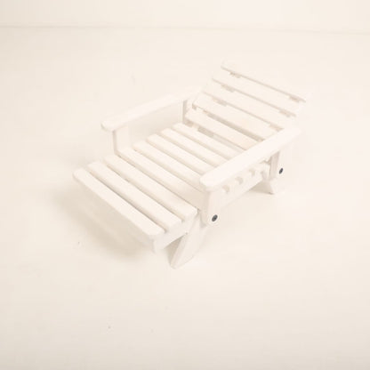 A mini wooden beach bench surrounded by sand and seashells, styled as a coastal-themed baby photoshoot prop for creating a beach-inspired setting.