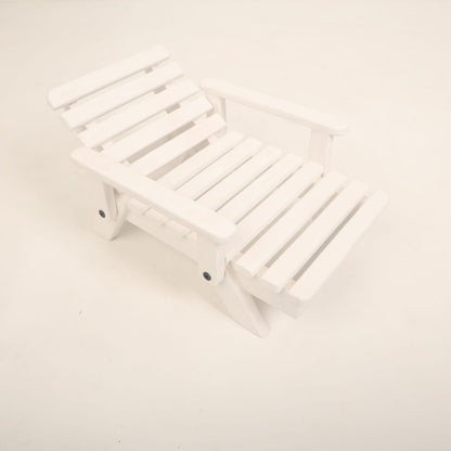 A mini wooden beach bench surrounded by sand and seashells, styled as a coastal-themed baby photoshoot prop for creating a beach-inspired setting.