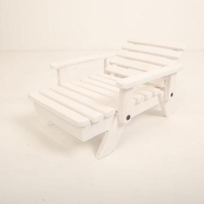 A mini wooden beach bench surrounded by sand and seashells, styled as a coastal-themed baby photoshoot prop for creating a beach-inspired setting.