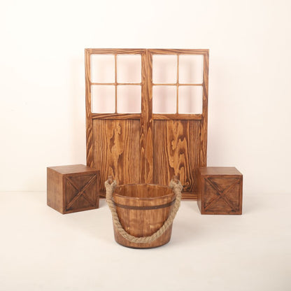 A complete newborn photography setup featuring a dual-shade double leaf door with one side wooden brown and the other in red or white, accompanied by two boxes placed on either side and a bucket for newborns.