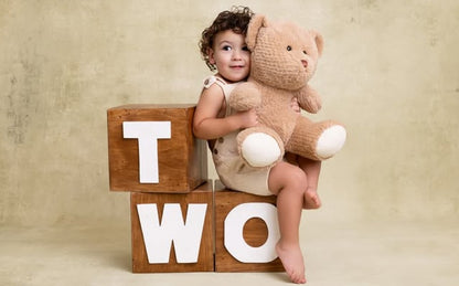 Two-year milestone photoshoot of a toddler sitting on a studio baby prop for photographers