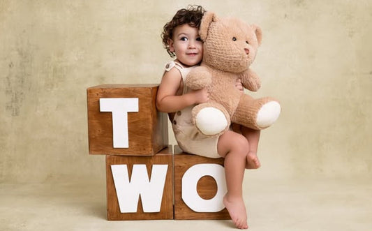 Two-year milestone photoshoot of a toddler sitting on a studio baby prop for photographers