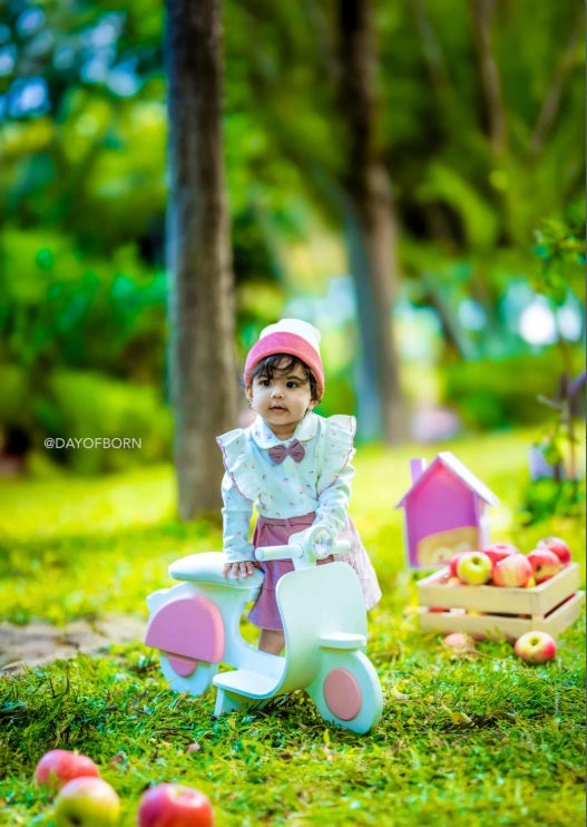 Baby standing near a scooter baby prop during a professional baby photoshoot.