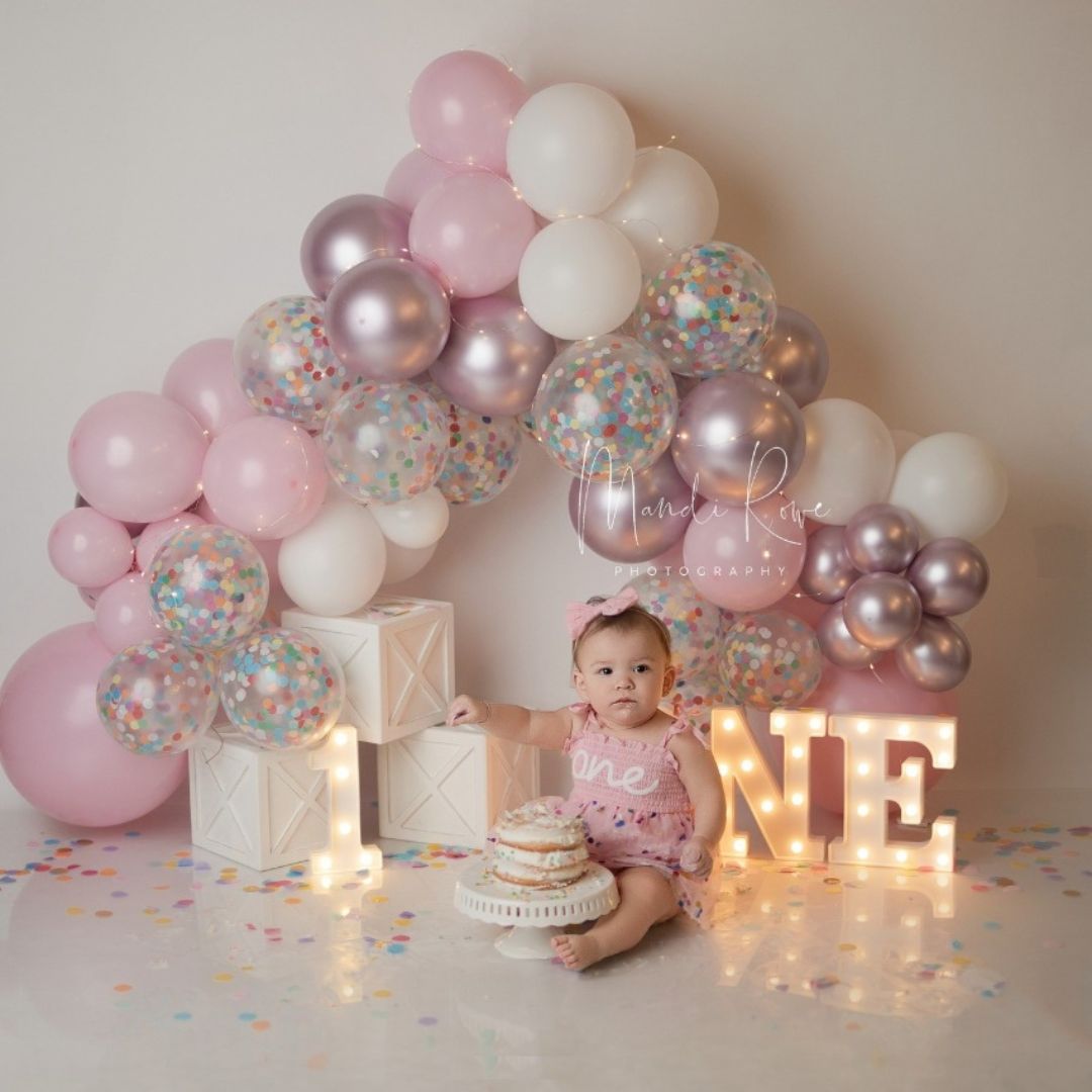 Cute baby sitting on studio floor decorated with milestone milestone boxes for baby photoshoot