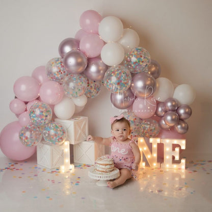 Cute baby sitting on studio floor decorated with milestone milestone boxes for baby photoshoot