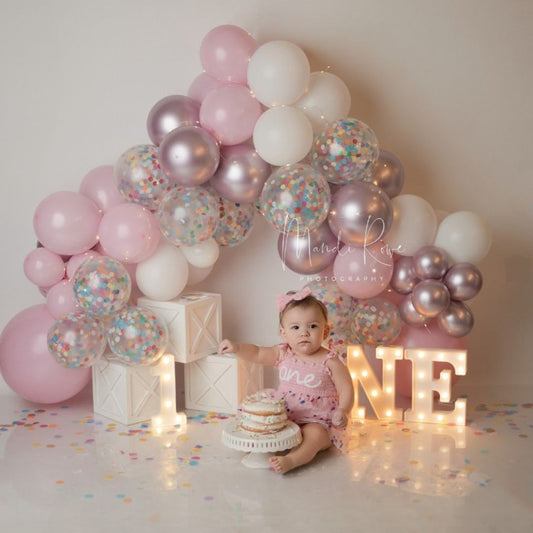 Cute baby sitting on studio floor decorated with milestone milestone boxes for baby photoshoot