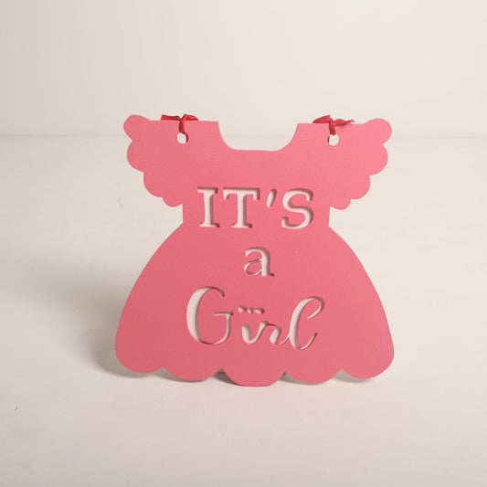 A stylish "It's a Girl" sign surrounded by pink flowers and soft pastel decorations, perfect for a maternity photoshoot or gender reveal.