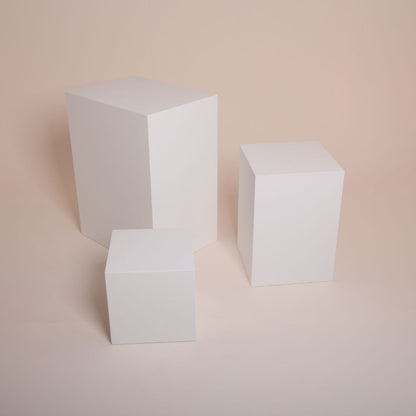 Model posing on white MDF cube in minimalist photo studio