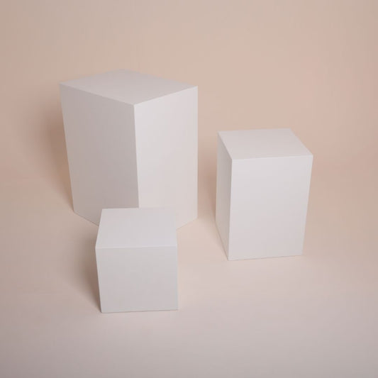 Model posing on white MDF cube in minimalist photo studio