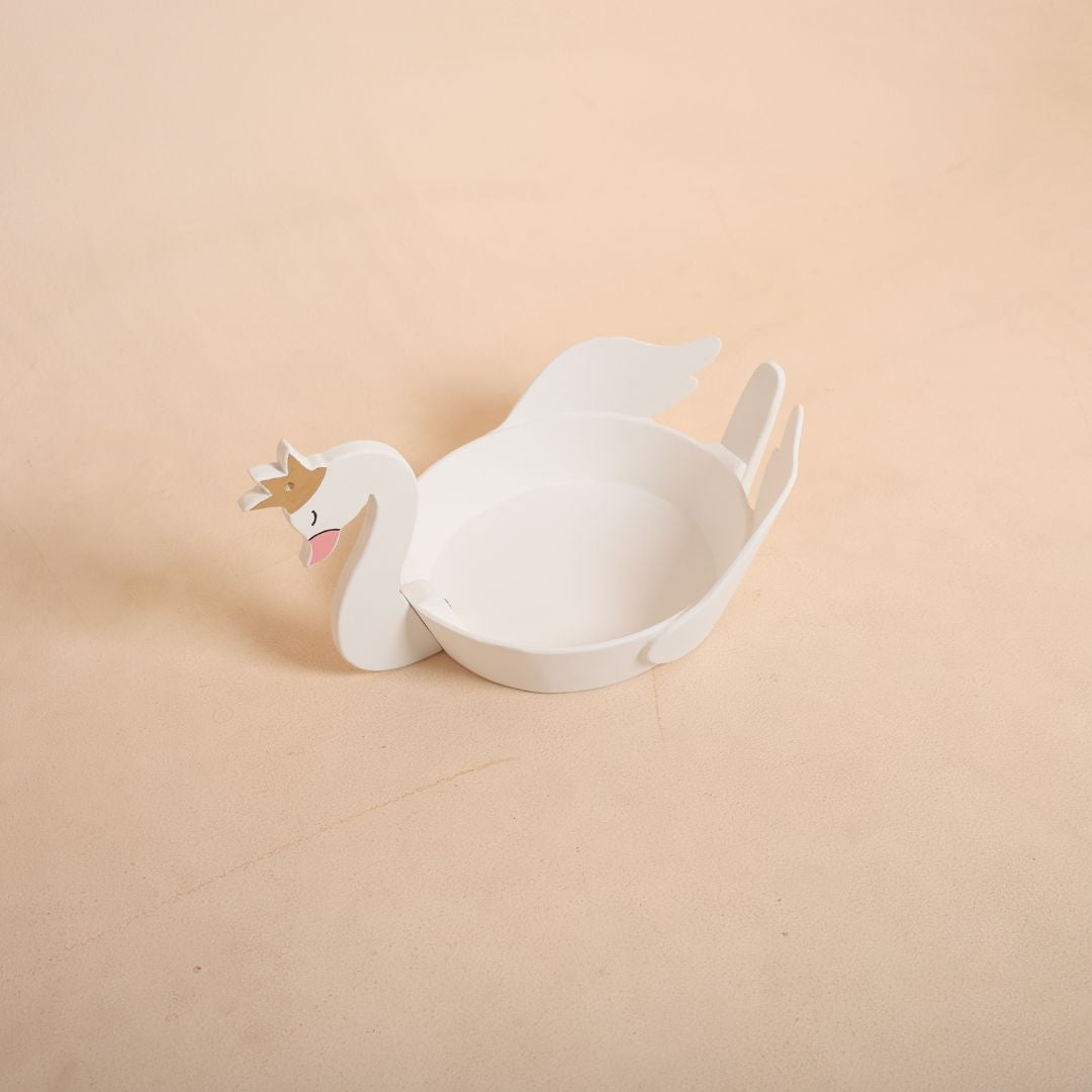 Newborn baby sleeping inside a white swan prop for an elegant and fairy-tale themed baby photoshoot.